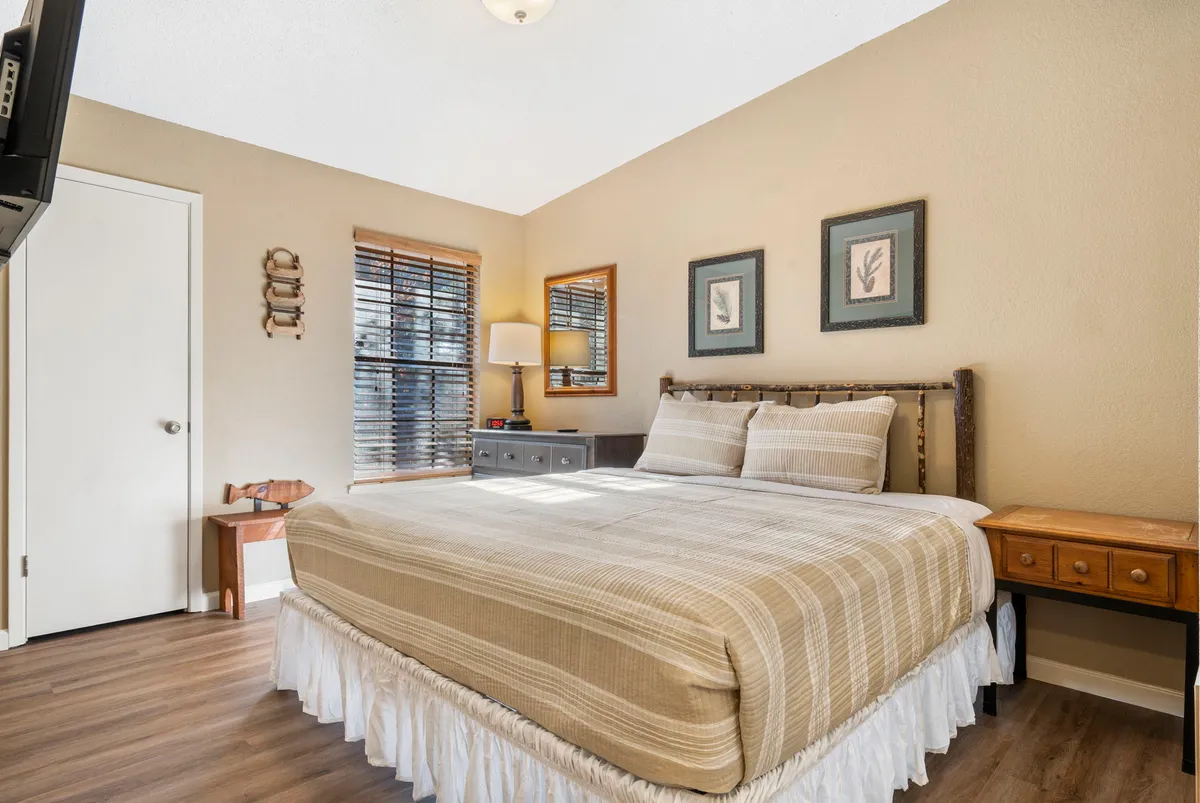 A cozy bedroom featuring a bed with striped bedding, matching nightstands, and modern wall art. The overall mood is calming, with gentle lighting creating a restful ambiance perfect for a romantic escape or a family getaway.