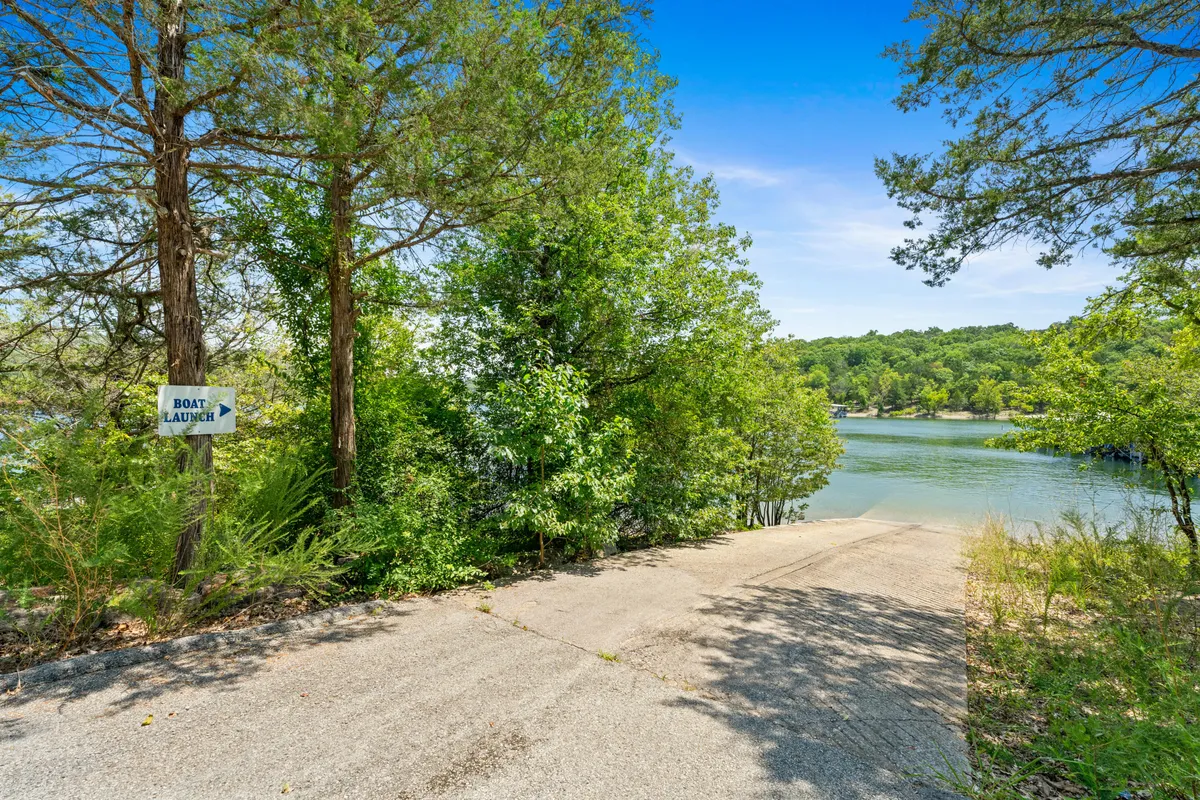 A lakeside view featuring a 'boat launch' sign at the water’s edge, surrounded by lush trees. Calm water stretches into the distance, inviting for boating and fishing. The scene evokes a sense of both easy lake access and tranquil outdoor adventure.