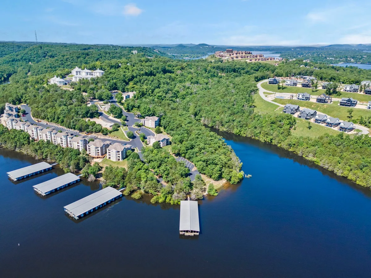 A tranquil view of waterfront docks, residential buildings nestled among lush greenery, and hillside homes in the background. The scene embodies the peaceful, nature-rich atmosphere ideal for exploring with a pet and enjoying outdoor moments by the water.