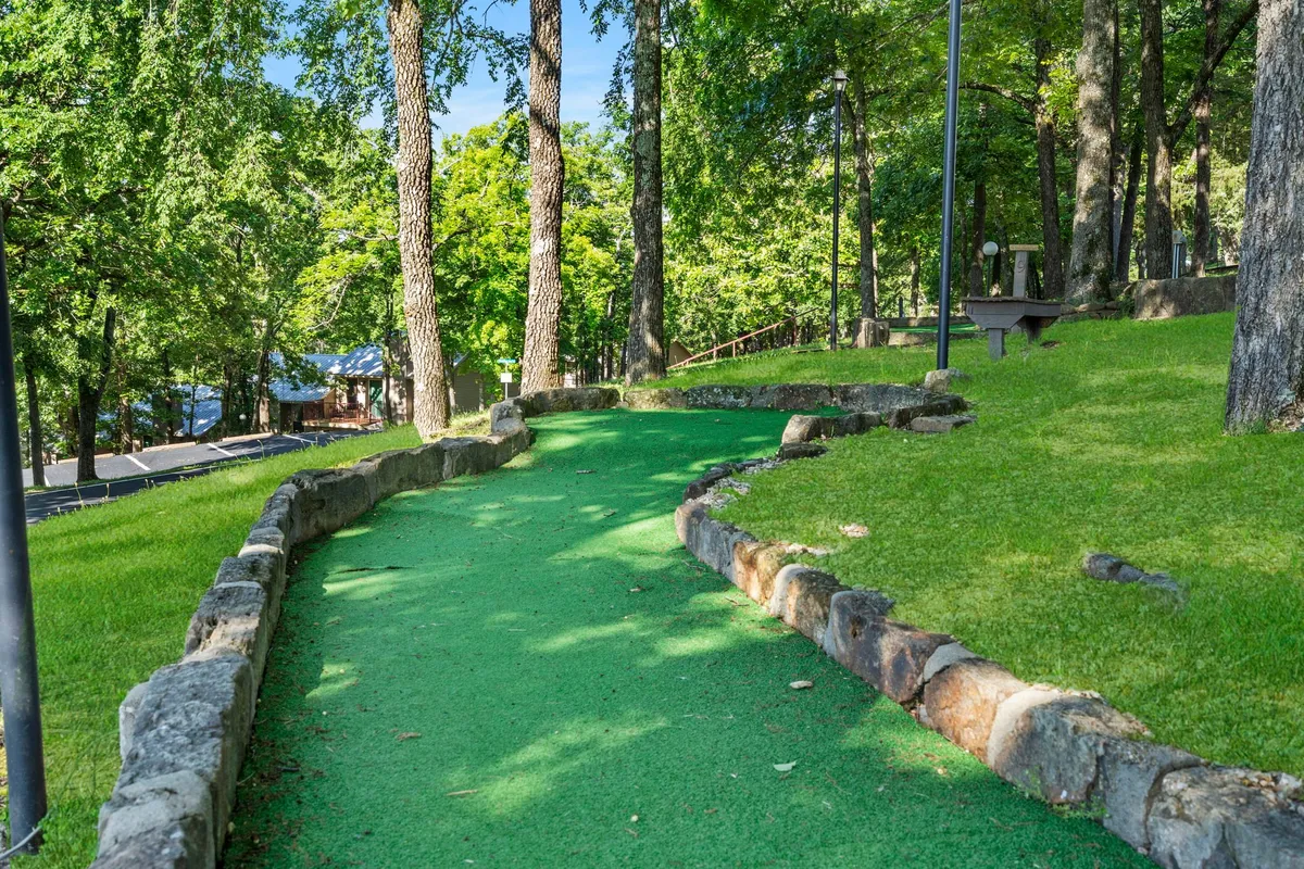 A playful stretch of the resort’s mini-golf pathway winds through mature trees and is bordered by stonework, inviting friendly competition and lighthearted family moments amidst nature.