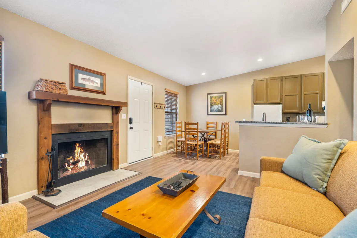 The hero image showcases a warm, inviting living area featuring a glowing fireplace, a comfortable sofa, a stylish coffee table, and a dining table set for family gatherings. The cozy ambiance is perfect for relaxing evenings and memorable moments with loved ones.