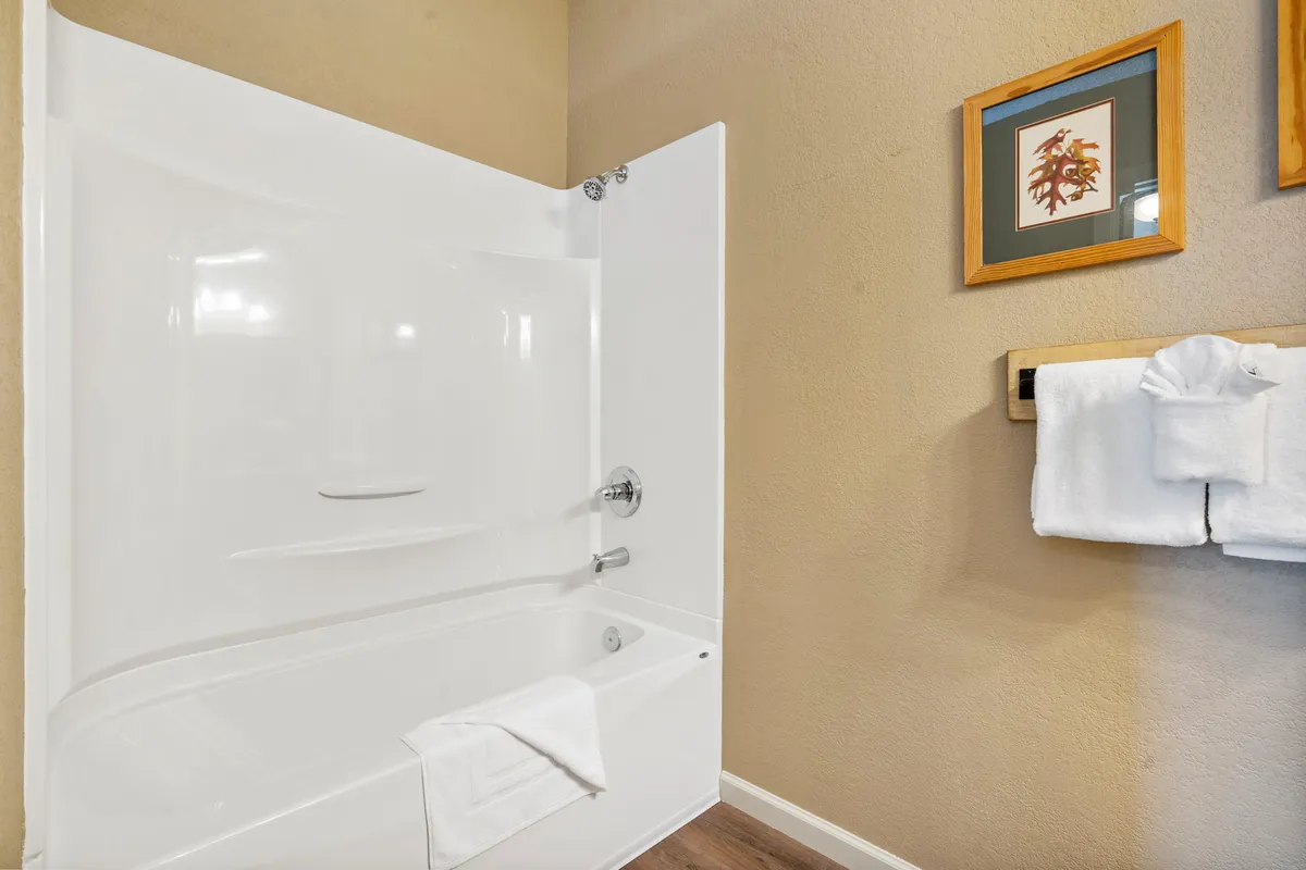 A sparkling clean bathroom with a bathtub, fluffy towels, and framed artwork. The space feels inviting for a hot soak or shower, promising relaxation after an active day at the lake.